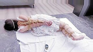 Shibari bondage technieken gebruikt op een vastgebonden en geknevelde brunette